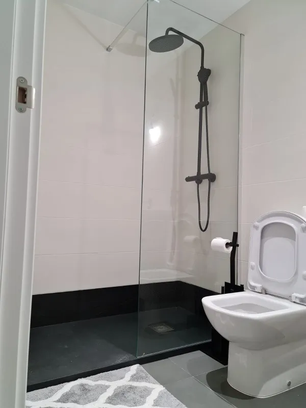 Bano reformado en Sabadell — bano moderno con plato de ducha y mampara